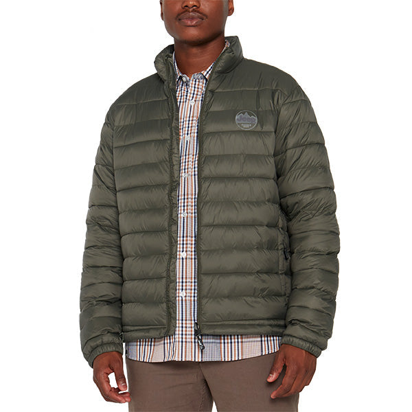 A man wearing a long sleeve murky green puffer jacket with a collar, over a striped shirt.