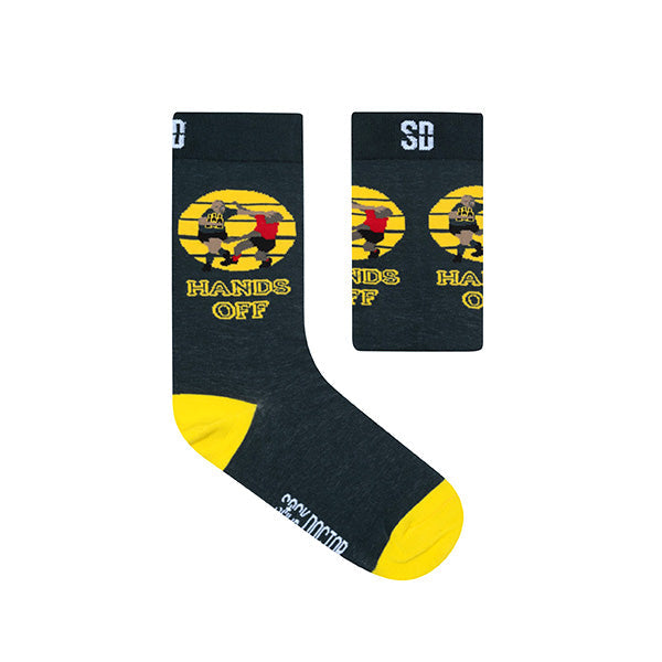 A pair of black socks with yellow accents on the heels and toes, featuring a graphic design of a character and text 'HANDS OFF' on the calf.