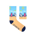 A pair of socks with a beach and surfboard design, predominantly blue and beige in color, with the brand name 'SOX DOCTOR' on the ankle area.