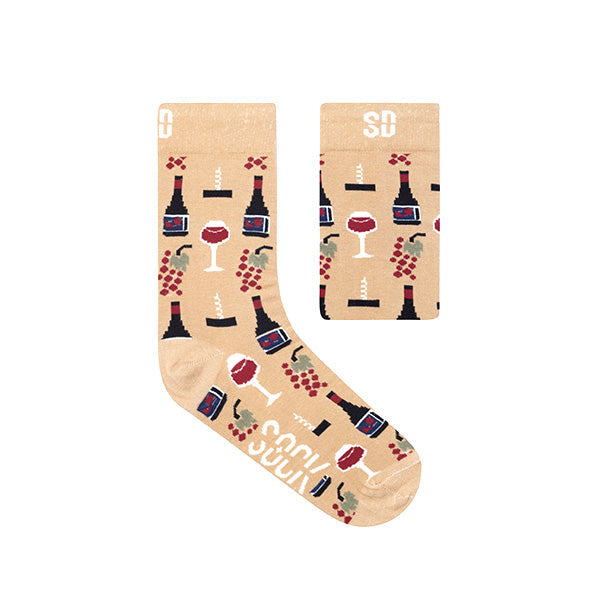 A pair of beige socks with wine-themed patterns including wine bottles, glasses, and grapes, along with the brand logo 'SD' from Sock Doctor.