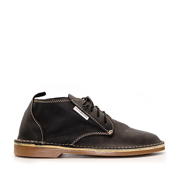 A high-cut, lace-up vellies shoe in black color with a visible sole and stitching details, on a white background.