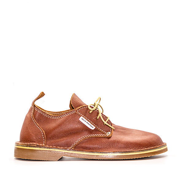A traditional South African Oukraal vellie shoe in Tan Rust color, featuring a low cut design and lace-up closure.