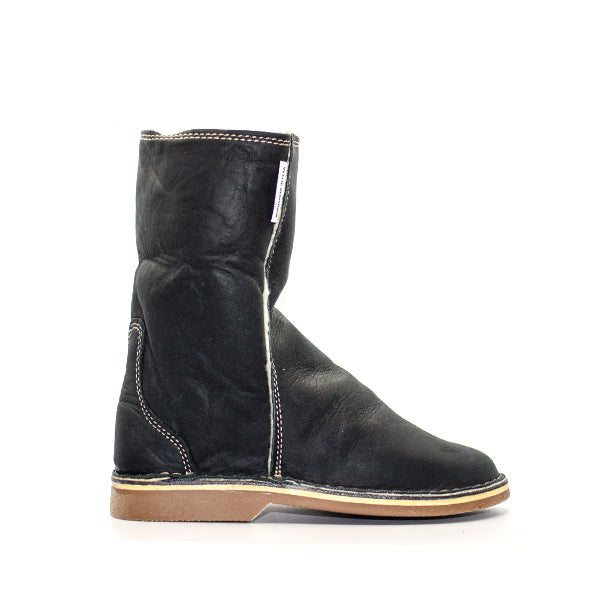 A black Oukraal SNUGG boot with a low heel and visible stitching on the shaft, set against a white background with a logo watermark above.