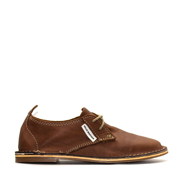 A tan brown vellie shoe with a low heel and lace-up closure.